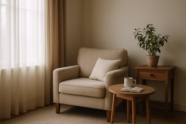 alt_text: A serene living room corner with soft morning light, featuring a cozy chair and coffee table.
