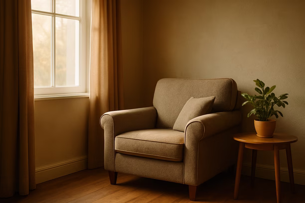 alt_text: A serene living room corner with an armchair and a potted plant in warm morning light.